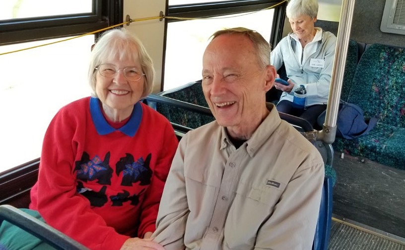 Two older riders smiling on board a bus